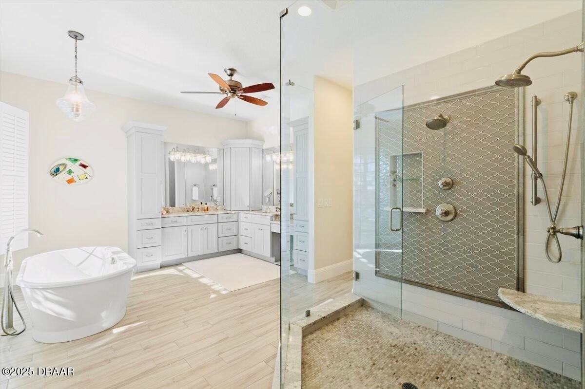 Bright bathroom with soaking tub, double vanity, and glass shower in white and beige tones
