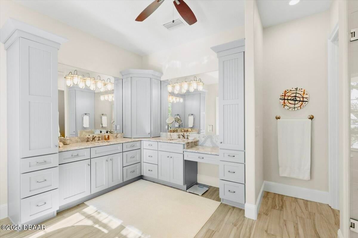 Bright white bathroom vanity with double mirrors, cabinets, and wood flooring