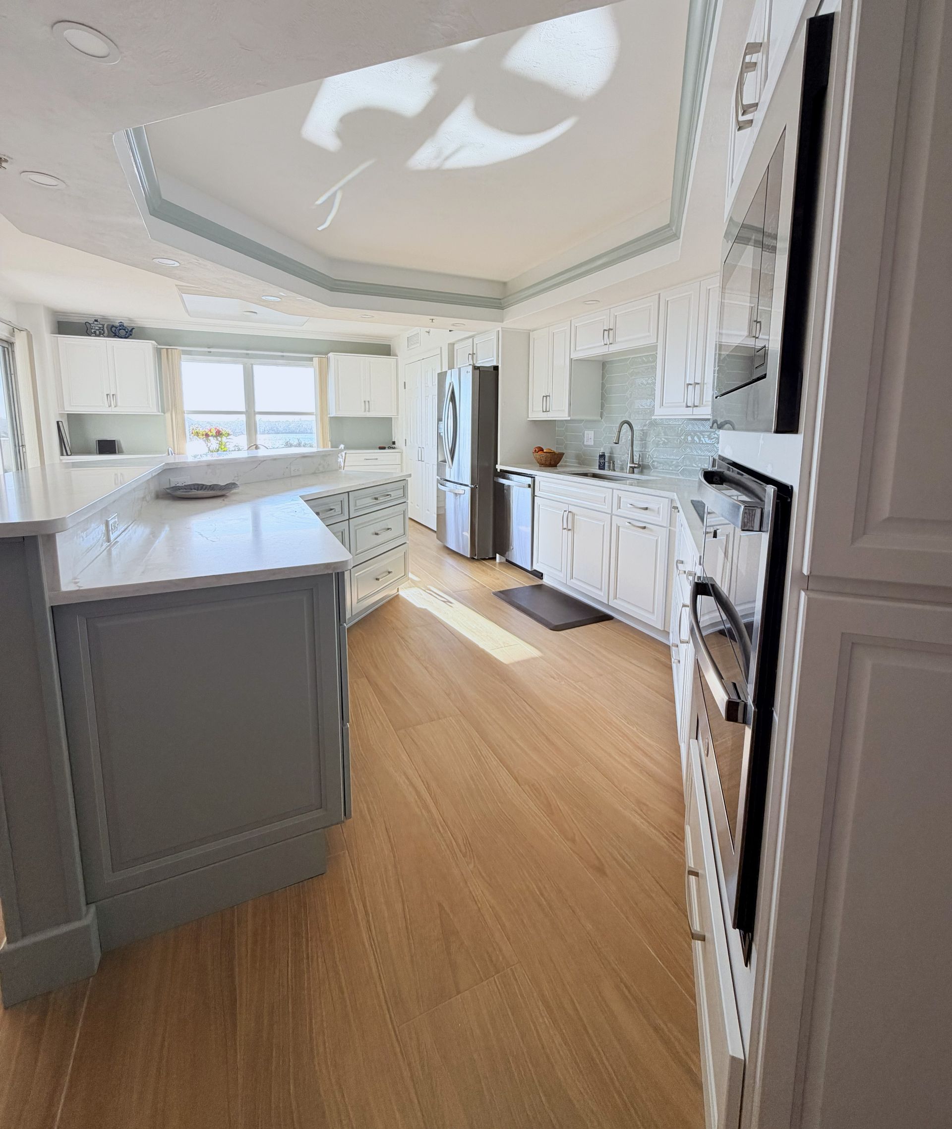 Bright white kitchen with island, light wood floor, and stainless steel appliances