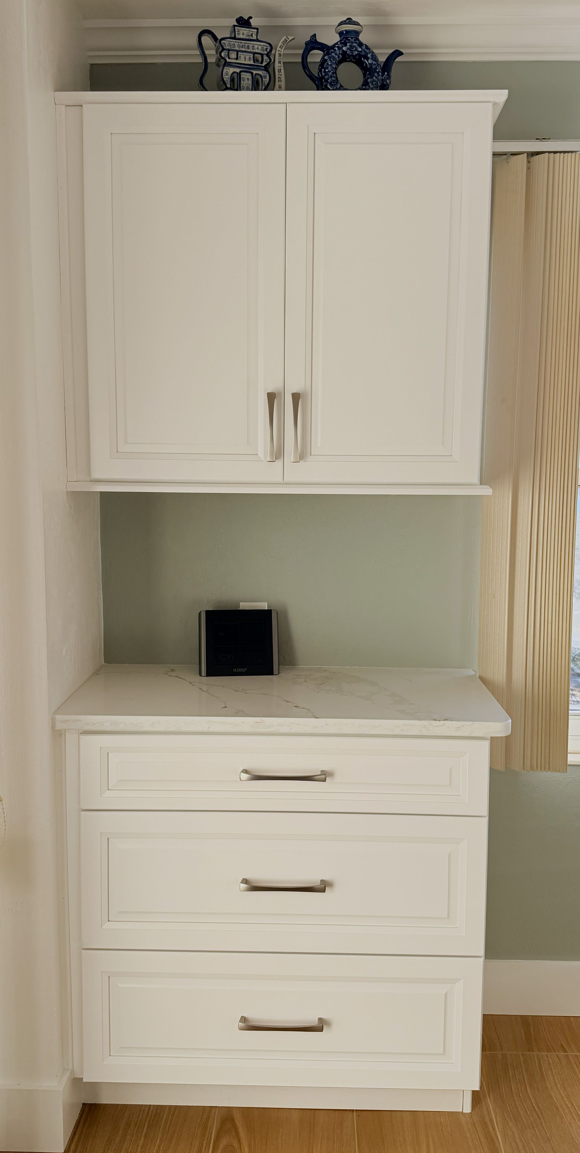 White cabinet and dresser in a hallway nook with decorative items on top