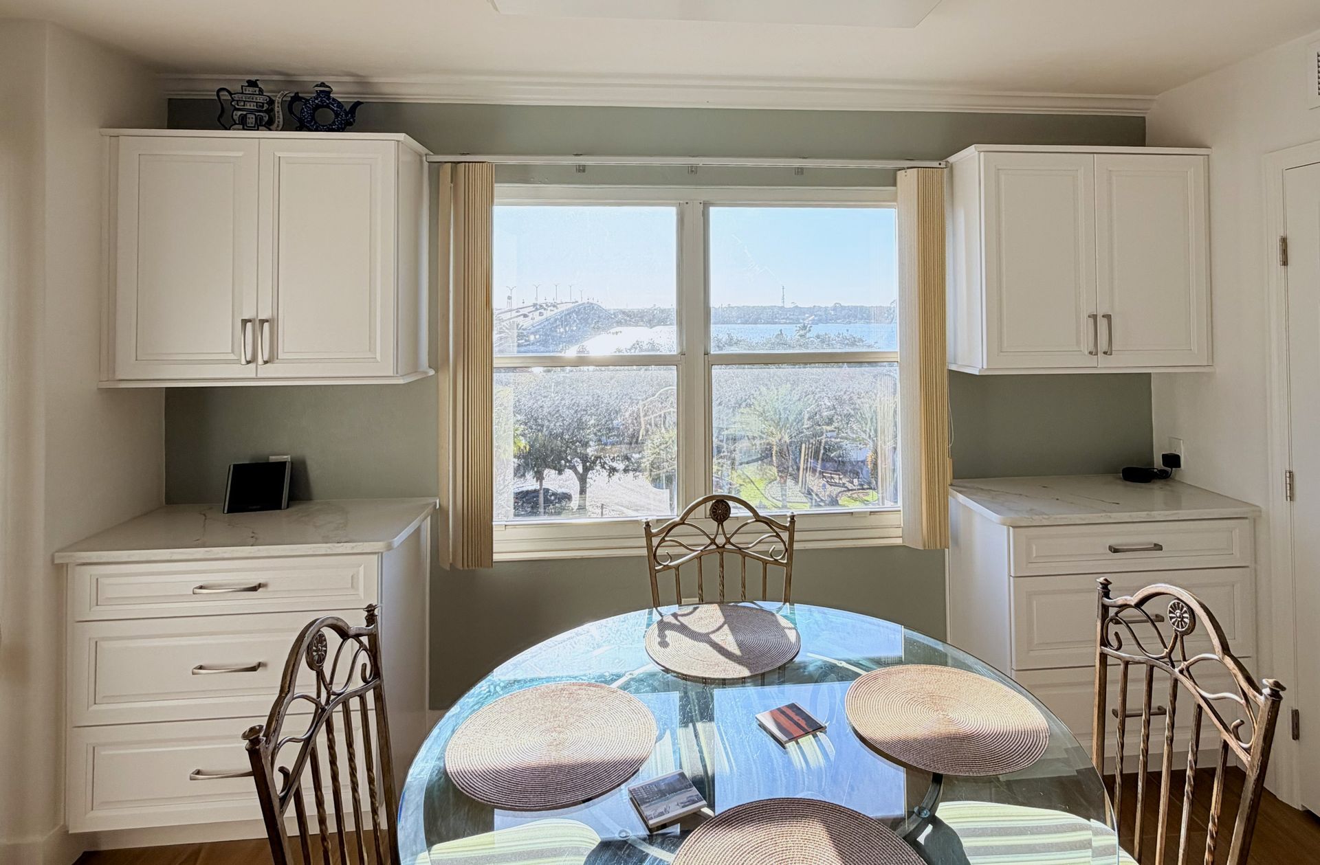 Bright dining nook with a round table, white cabinets, and a snowy river view through the window.