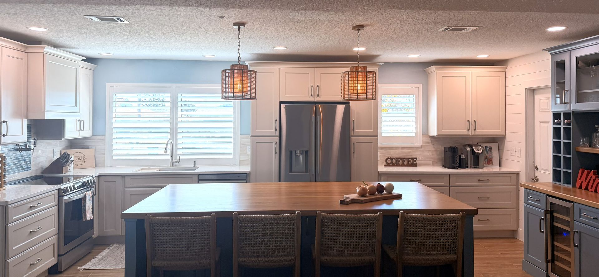Bright modern kitchen with a large island, white cabinets, stainless fridge, and pendant lights