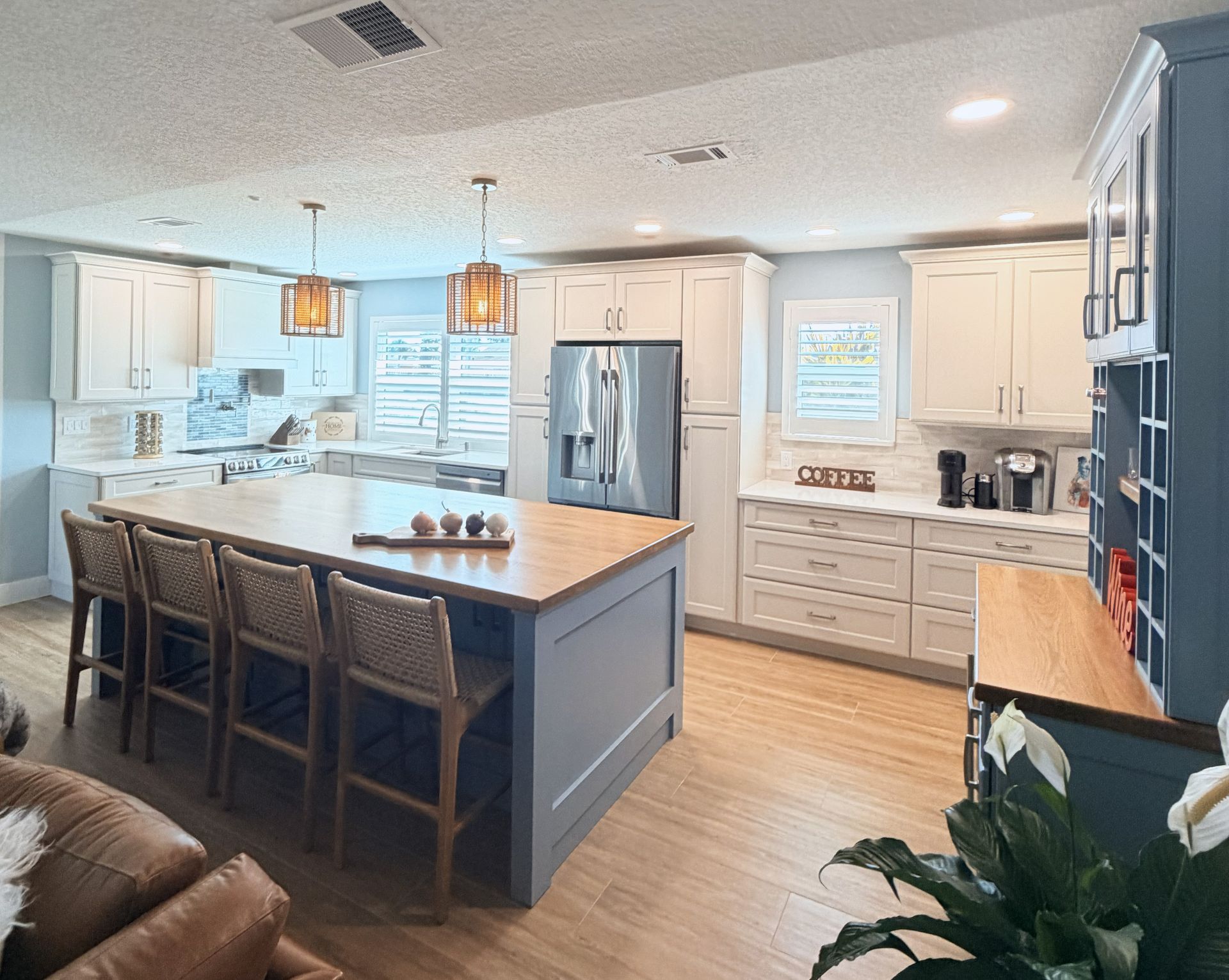 Bright modern kitchen with navy island, white cabinets, pendant lights, and barstools