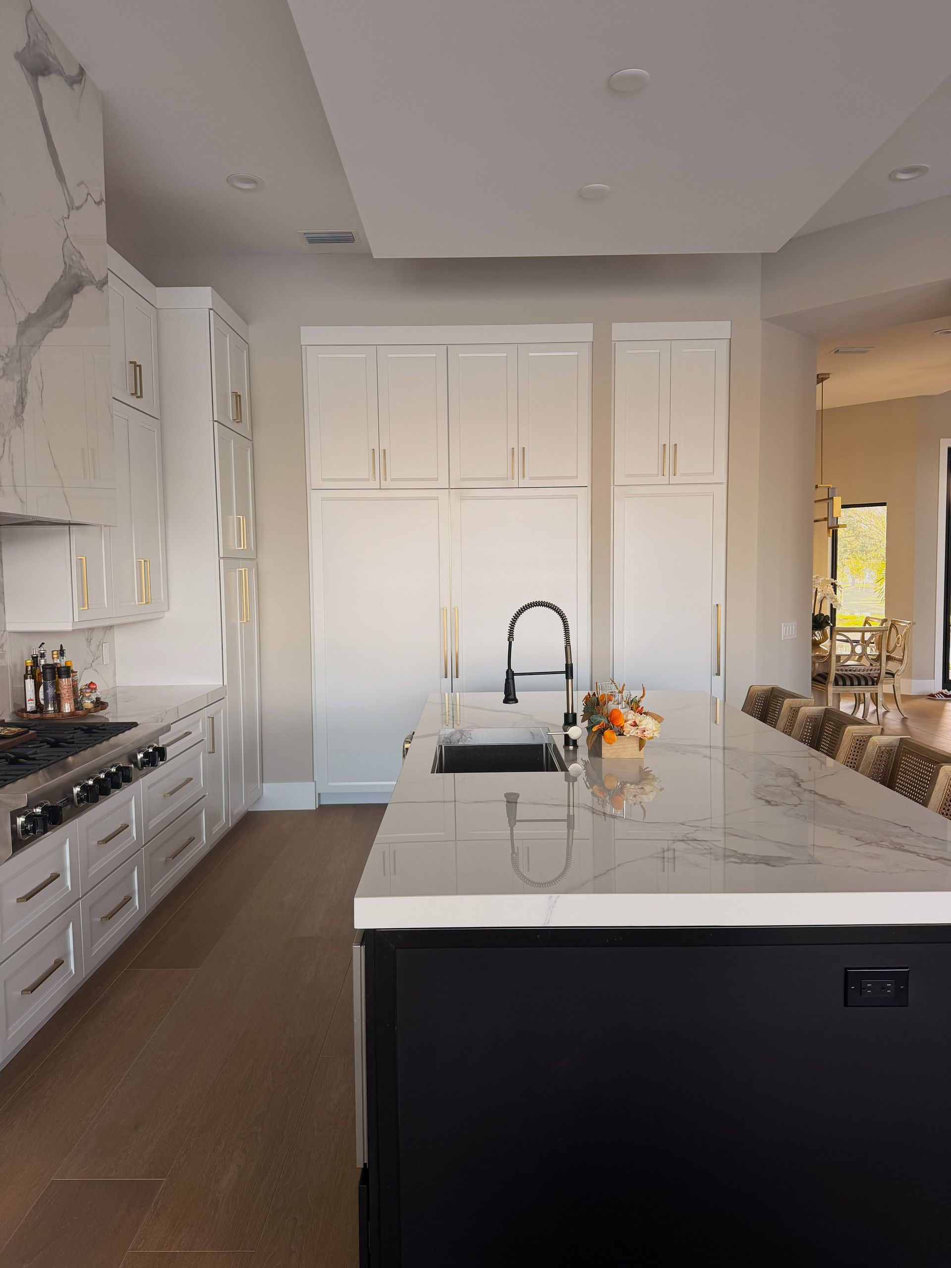 Modern white kitchen with large island, marble countertops, and built-in cabinets