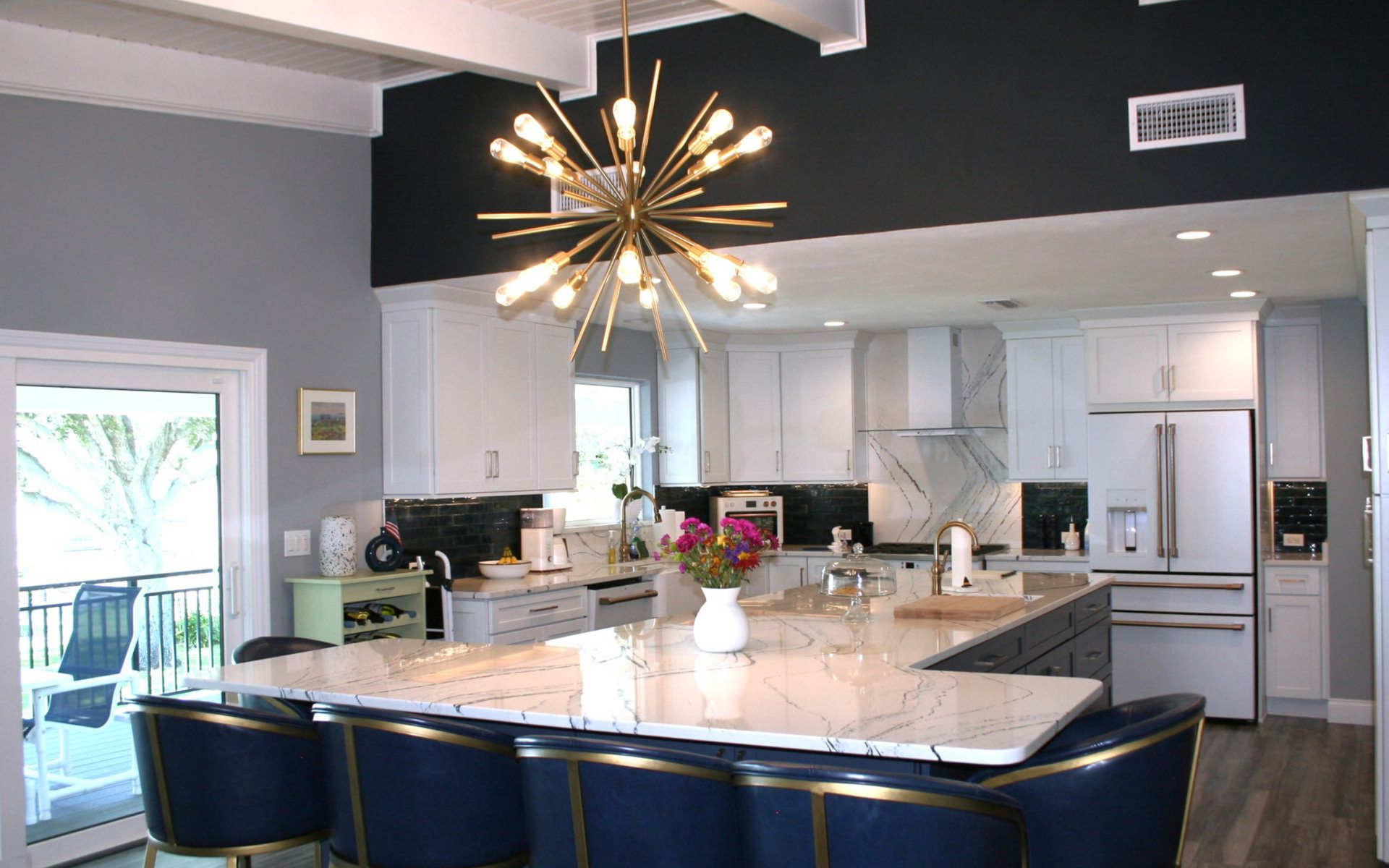 Modern kitchen with marble island, blue barstools, and starburst pendant light