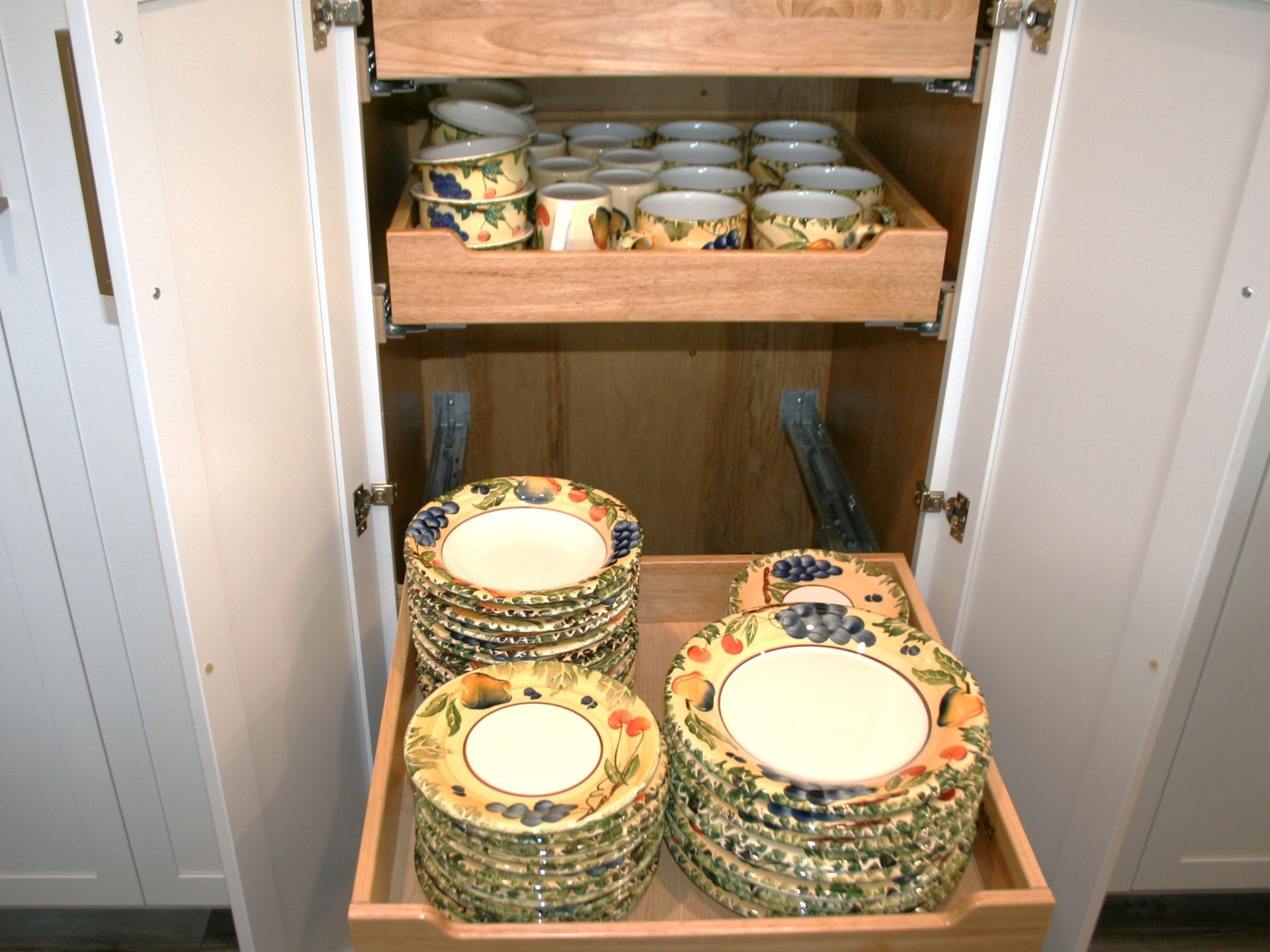 Open kitchen cabinet with stacked colorful plates and bowls on two shelves