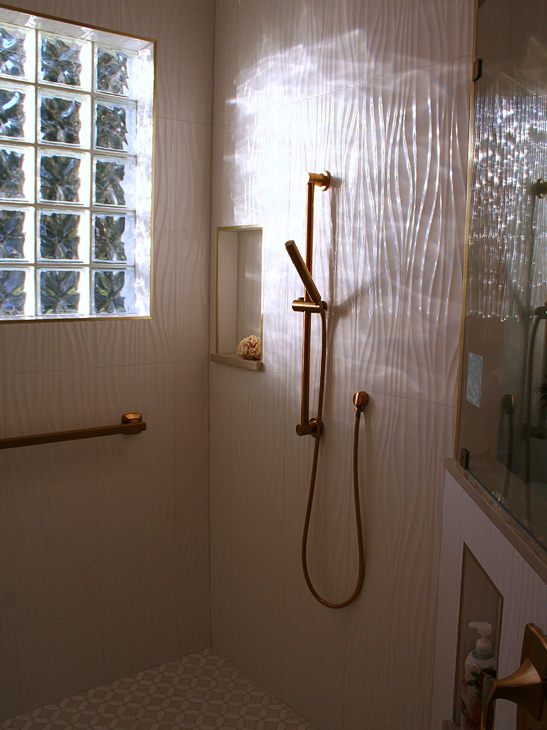 Bathroom with a shower, glass block window, and chrome grab bars beside a bathtub