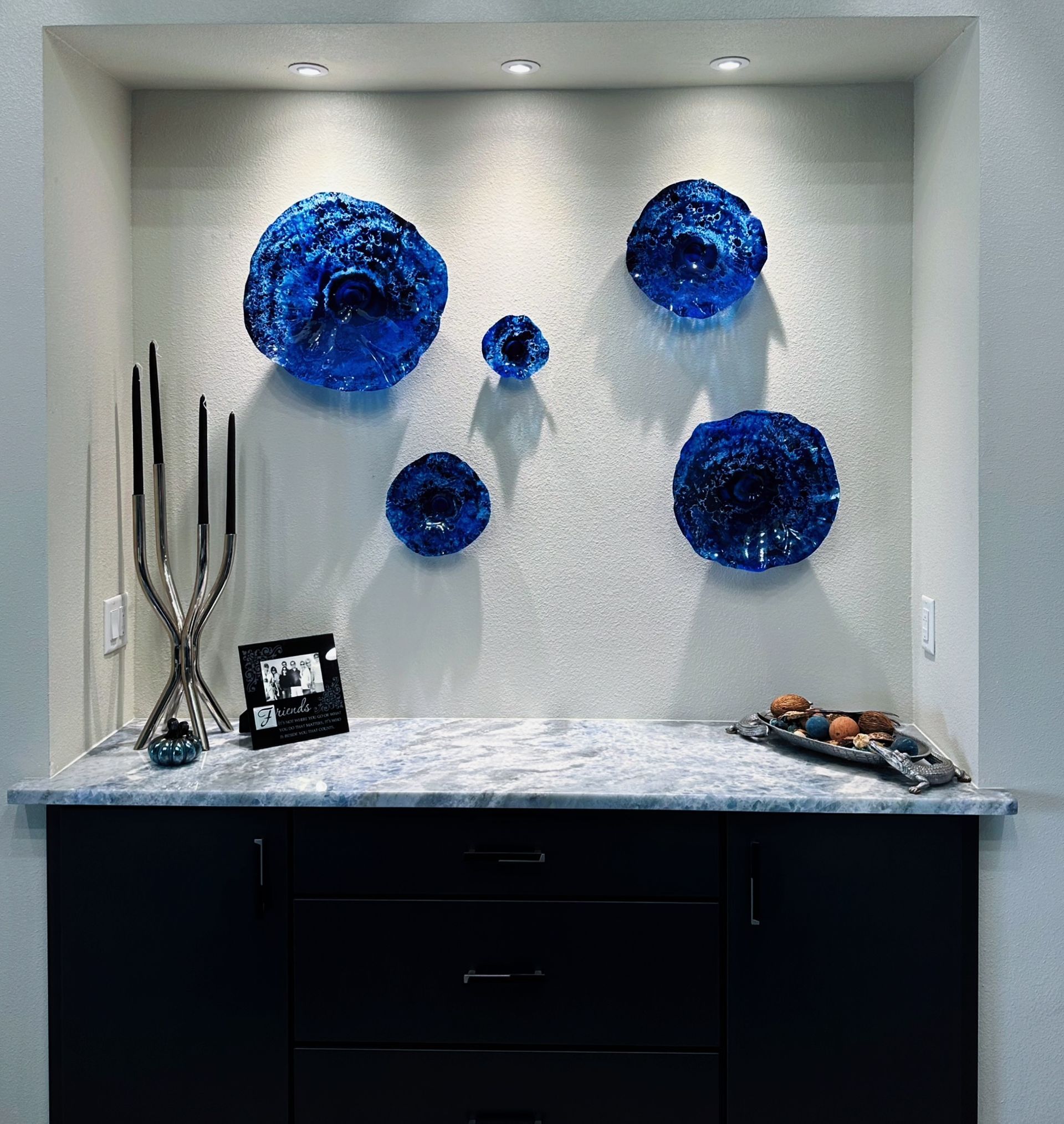 Modern wall niche with blue glass wall art above a marble counter and black cabinetry