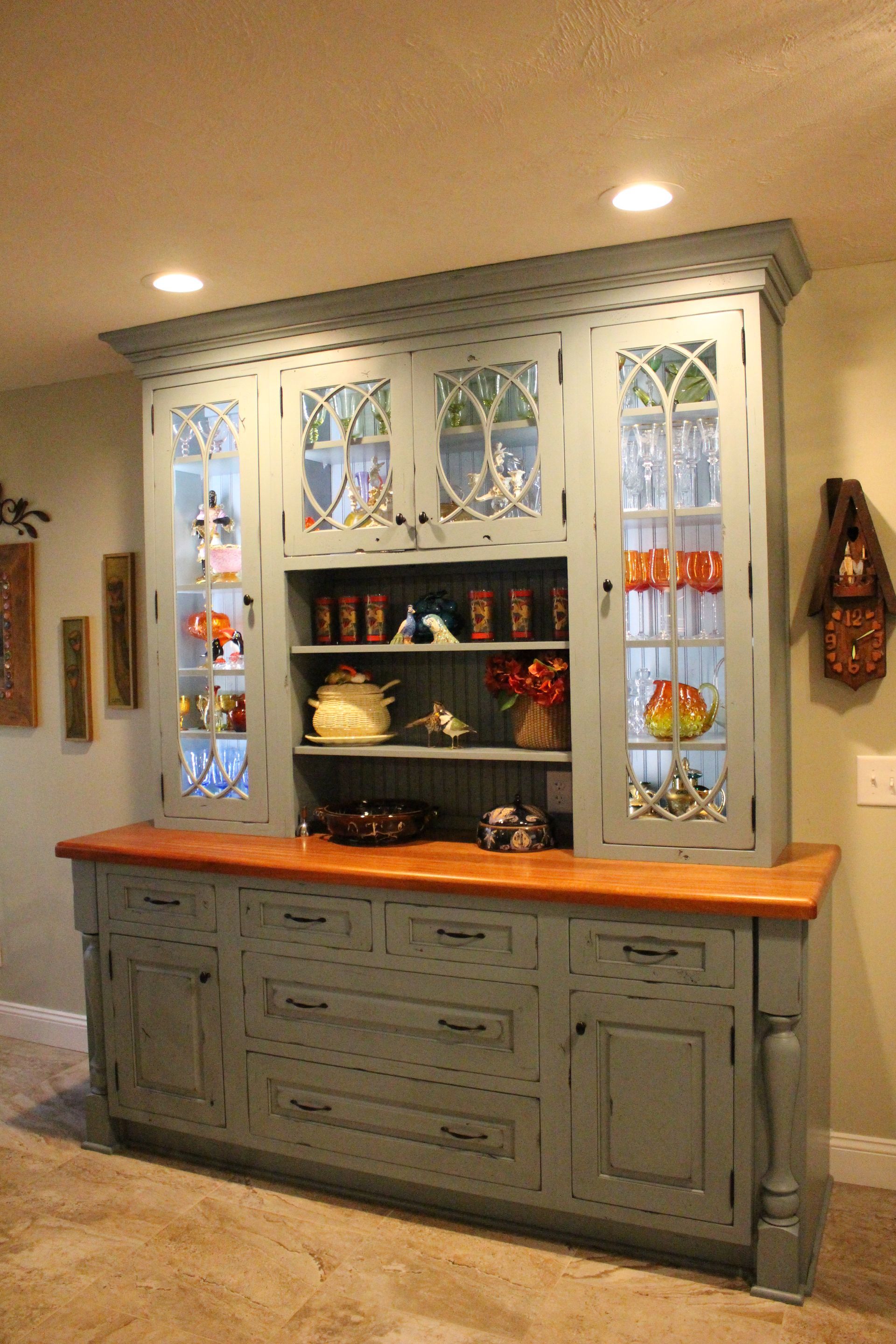Built-in hutch with stained glass doors and gray cabinet in a warmly lit room