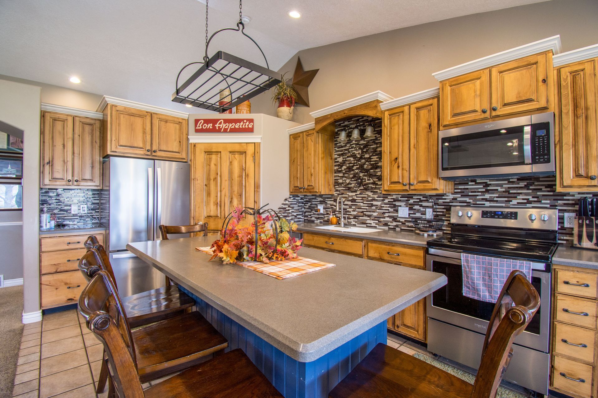 Modern kitchen with wood cabinets, stainless appliances, island, and two bar stools