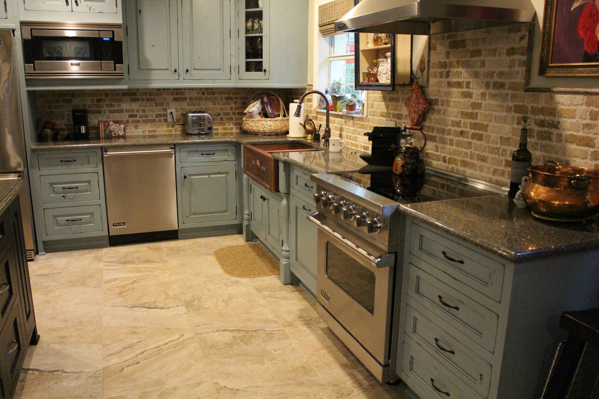 Modern kitchen with gray cabinets, stainless steel appliances, stone countertops, and beige tile floor