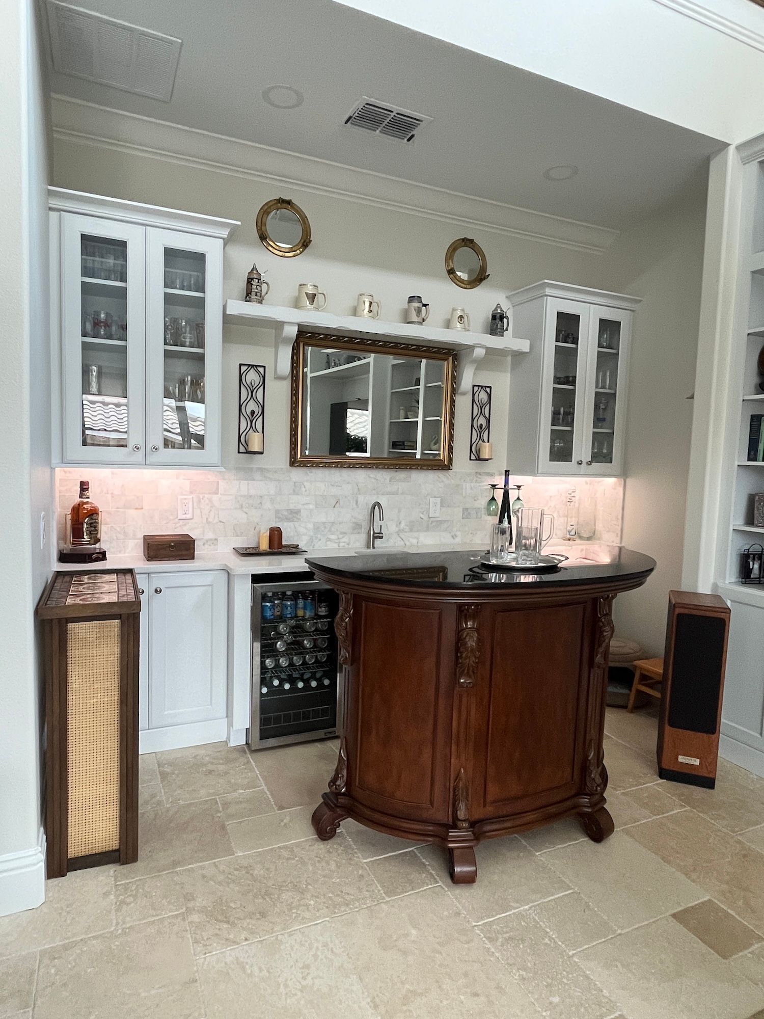 Elegant kitchen bar with dark wood island, white cabinets, wine fridge, and mirrored backsplash