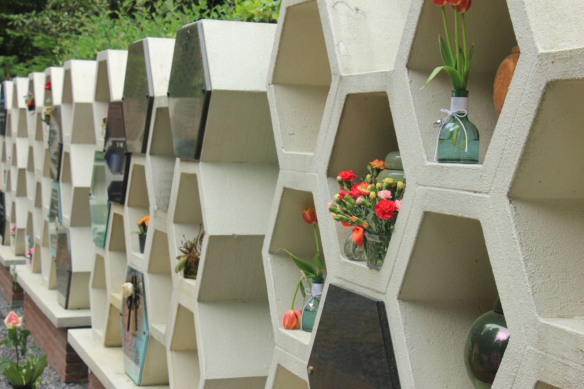Row of honeycomb-shaped niches with flowers and mementos in a columbarium. Row of honeycomb-shaped niches with flowers and mementos in a columbarium.