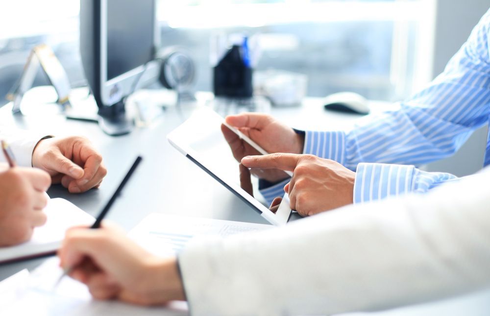 Hands Using a Tablet and Pens in a Bright Office Meeting — Emmel Finance in Townsville, QLD