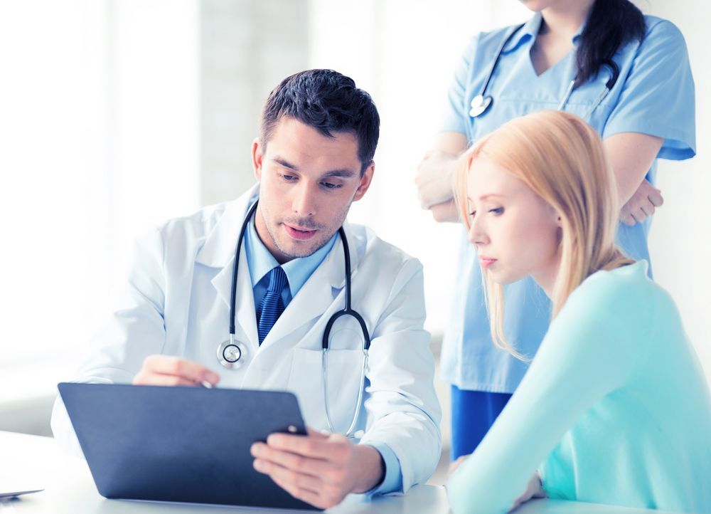 A Doctor And Nurse Are Looking At A Tablet With A Patient — Emmel Finance in Townsville, QLD
