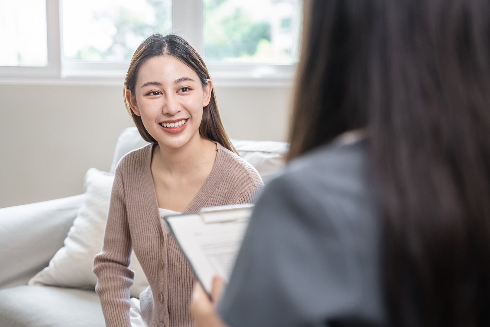 A Woman Is Sitting On A Couch Talking To A Financial Advisor — Emmel Finance in Townsville, QLD