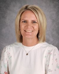 Portrait of a smiling woman in a white blouse against a gray studio backdrop