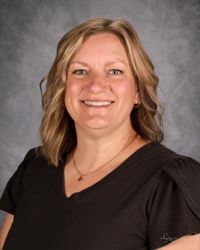 Smiling person in a black top against a gray studio backdrop