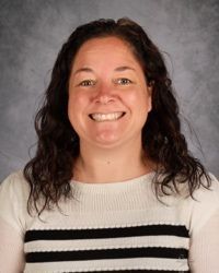 Smiling woman in a white-and-black striped sweater against a gray backdrop