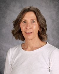 Portrait of a smiling woman in a white shirt against a gray studio backdrop