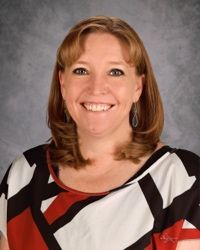 Smiling woman in a black, white, and red patterned top against a gray backdrop