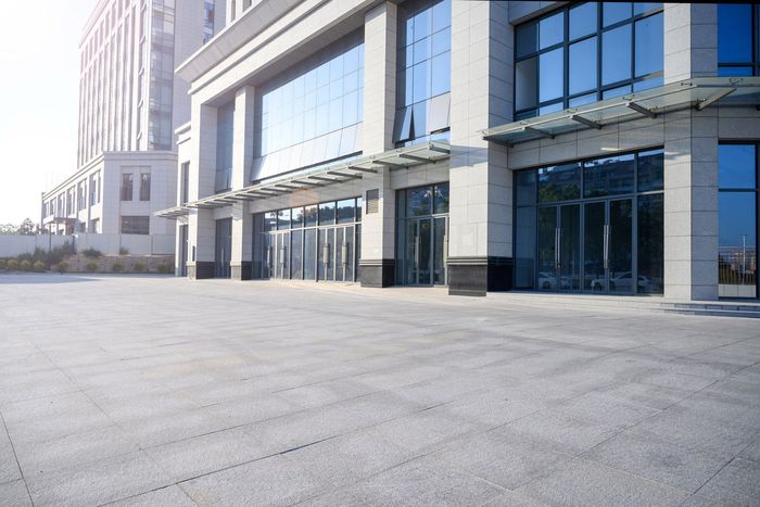 An empty parking lot in front of a large building with a lot of windows. An empty parking lot in front of a large building with a lot of windows.