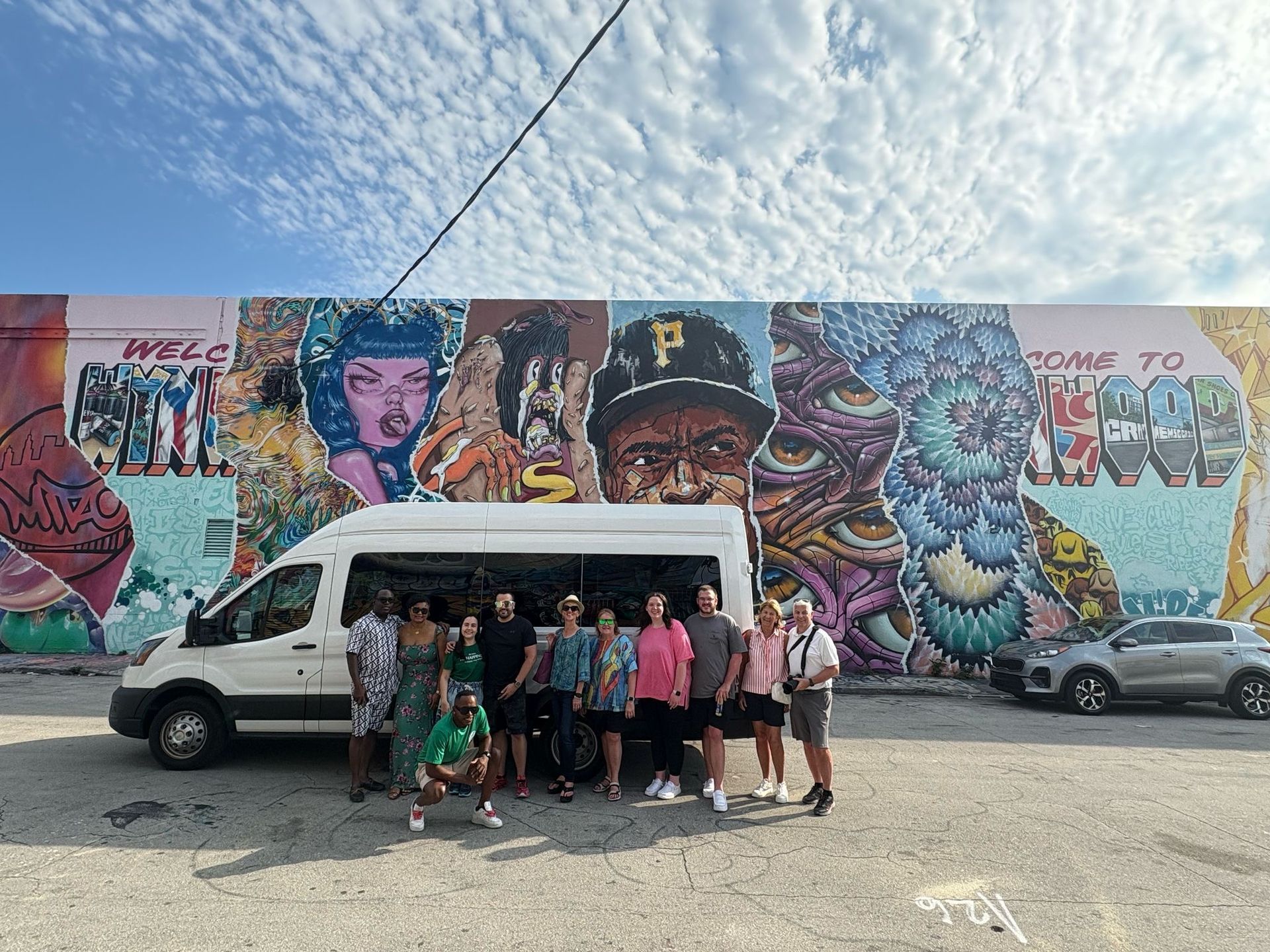 Miami hop off tour driver and passengers taking photos together at Wynwood Walls during the guided walking tour stop.
