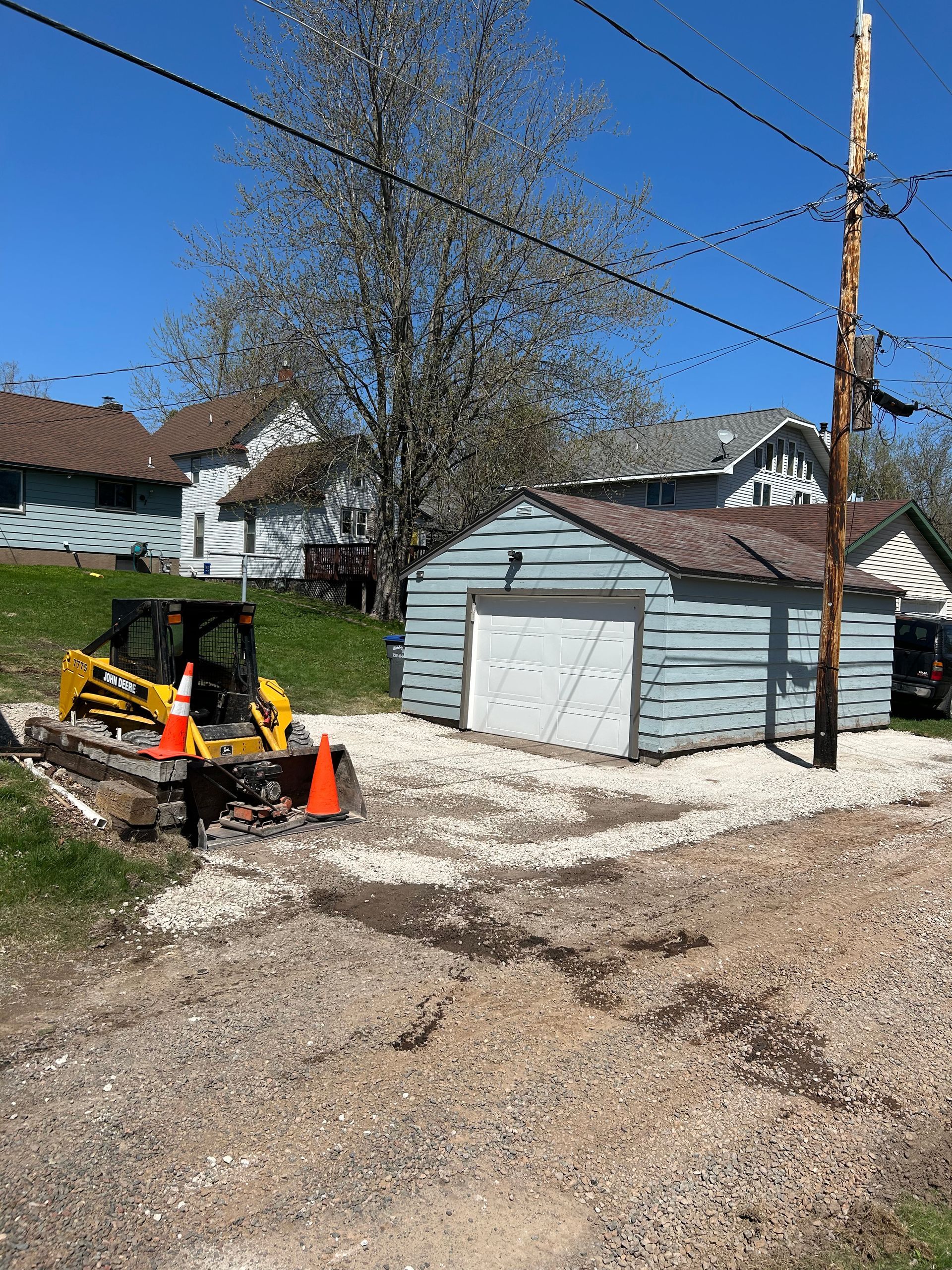 A yellow bulldozer is parked in front of a garage.