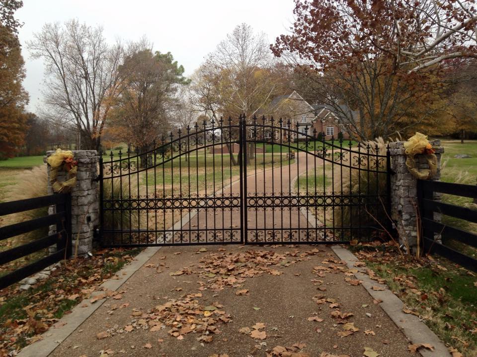 a wrought iron gate surrounds a driveway leading to a house American Fence & Gate, LLC 