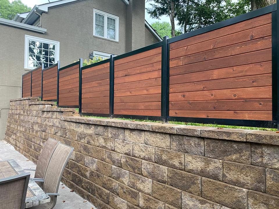 a wooden fence surrounds a brick wall in front of a house .