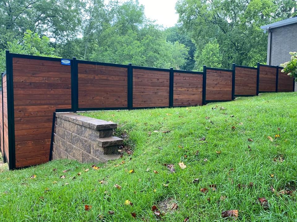 a wooden fence is sitting on top of a lush green hillside .
