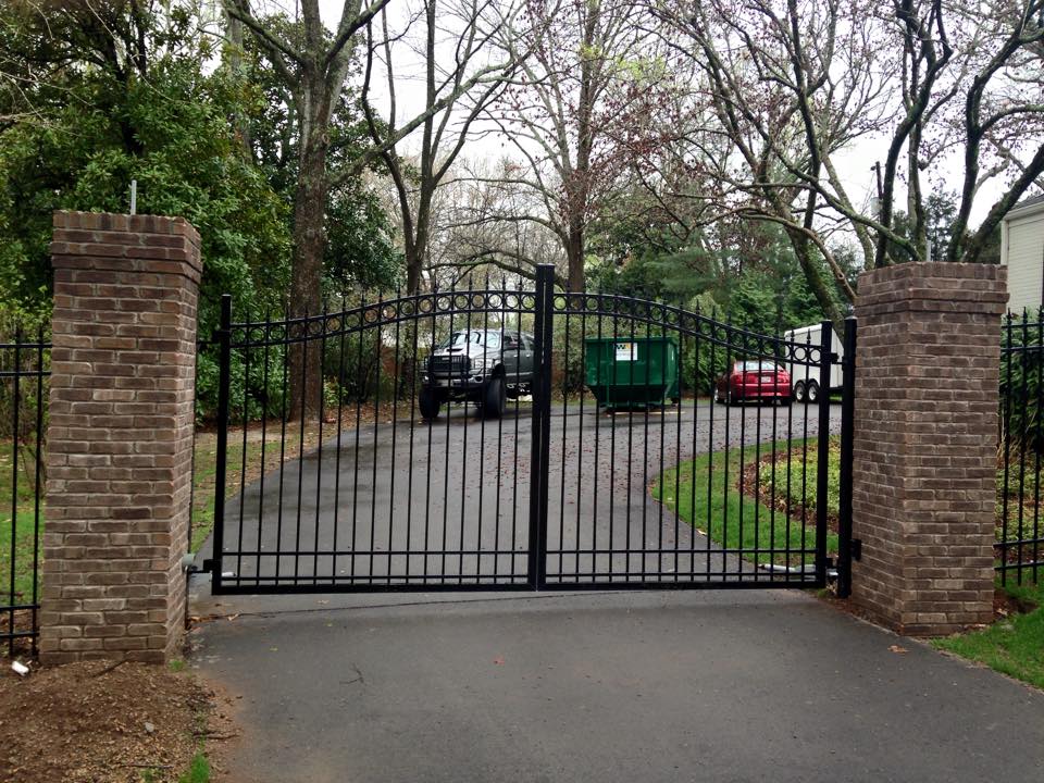 a black wrought iron gate is open to a driveway .