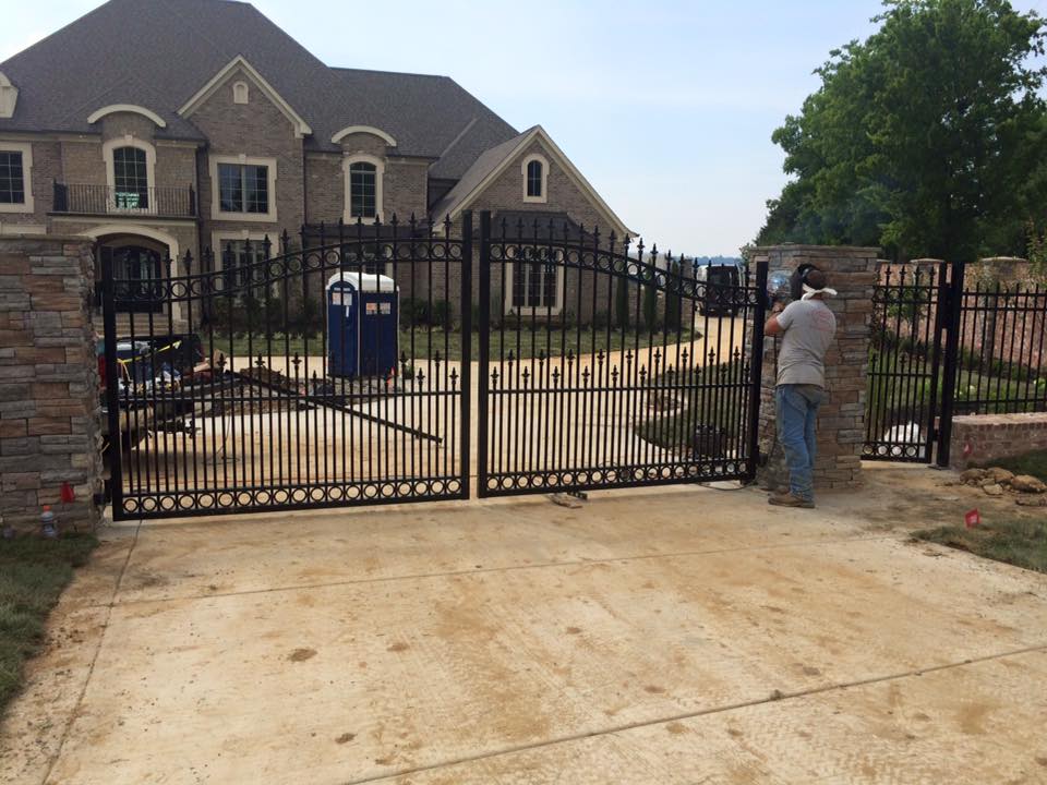 a man is working on a gate in front of a large house .