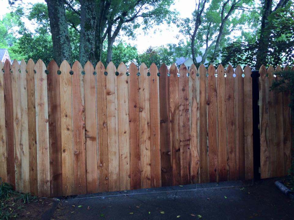 a wooden fence surrounds a driveway with trees in the background .