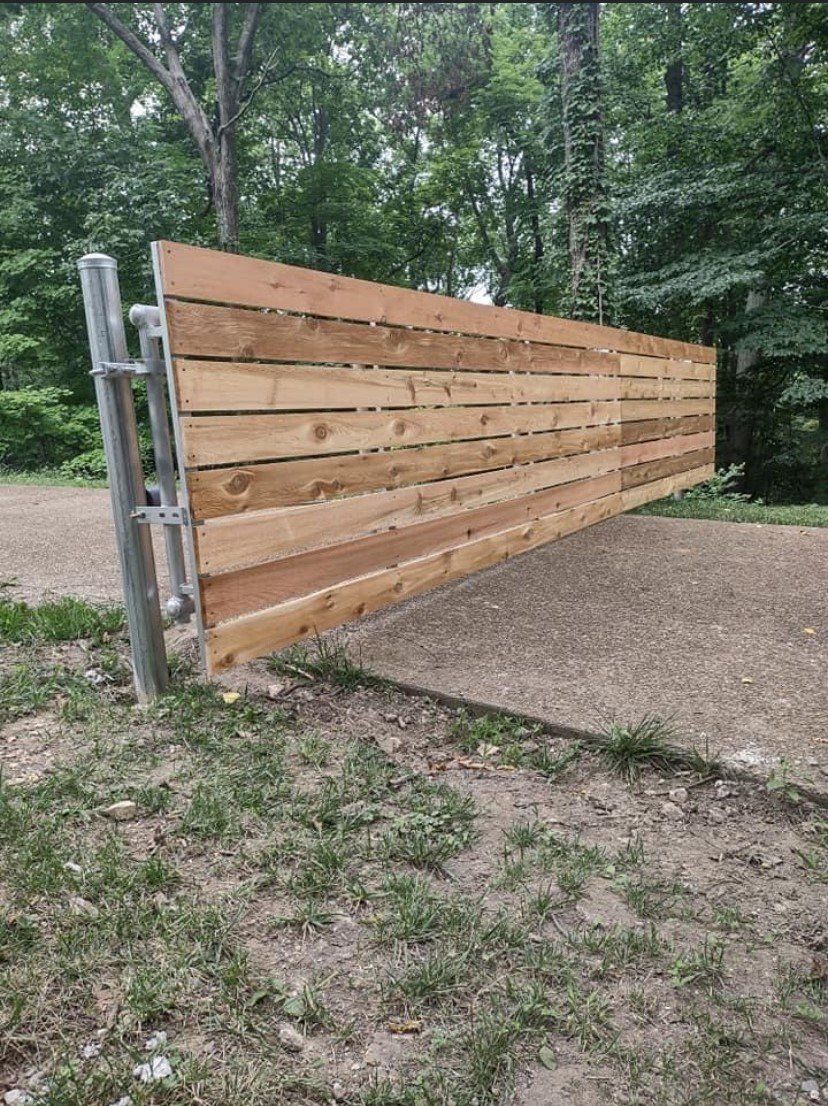 a wooden fence is sitting in the middle of a dirt field .