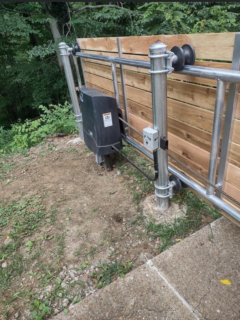 a sliding gate with a motor attached to it is sitting next to a wooden fence .