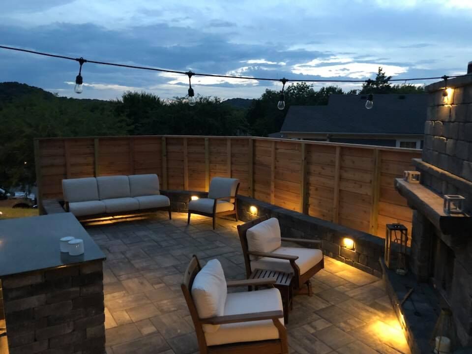 a patio with a couch and chairs is lit up at night