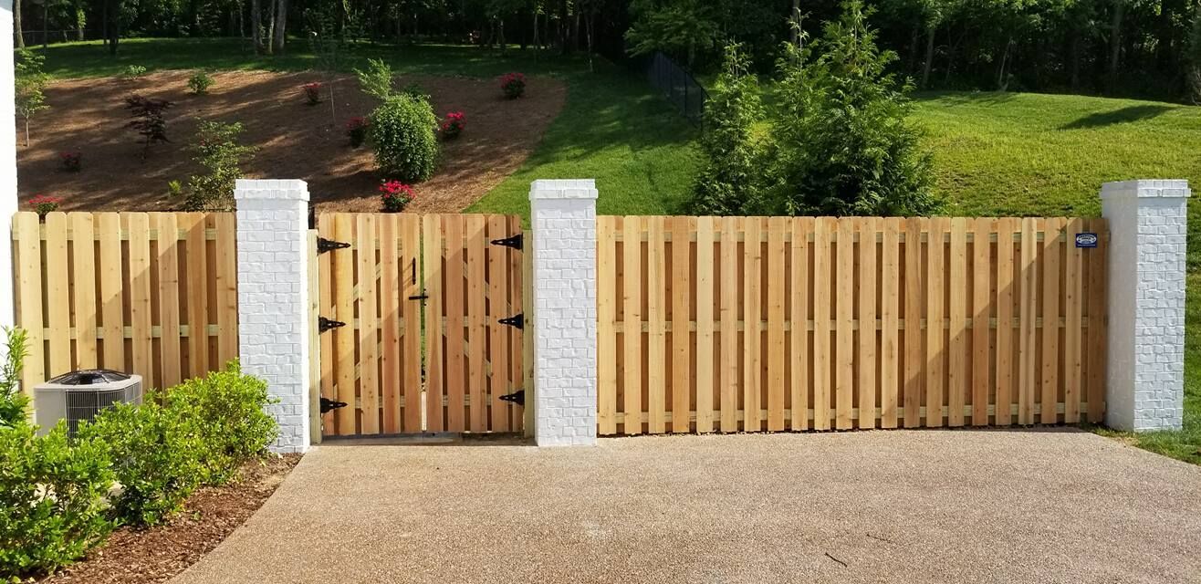 a wooden fence with a gate in the middle of a driveway .