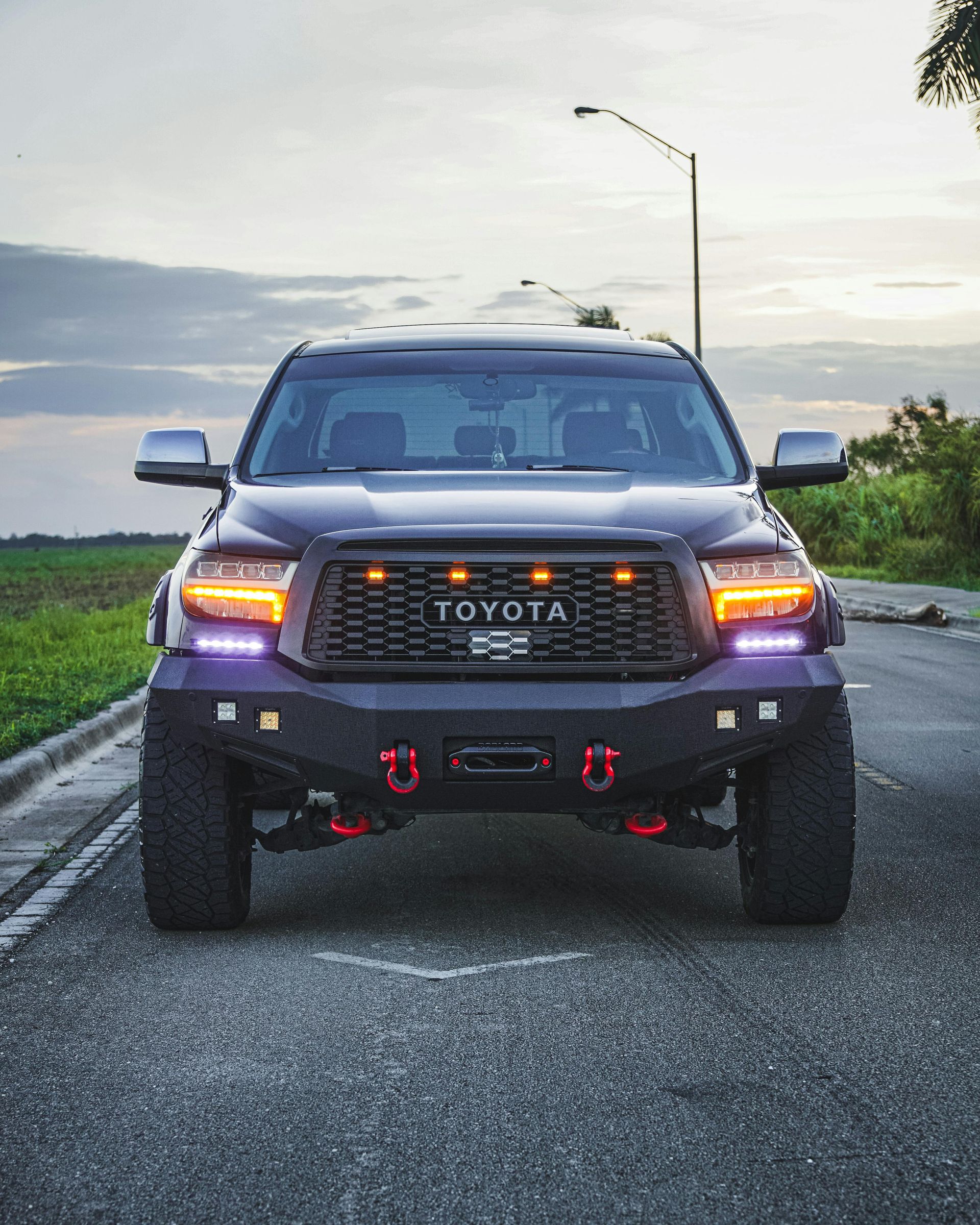 Dark Toyota Tundra truck with a black grille and off-road bumper on a road.