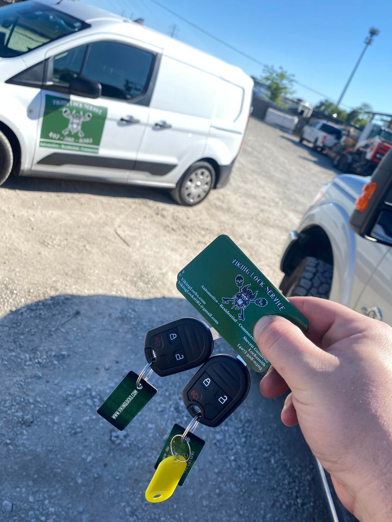 A person is holding a car key in front of a white van.