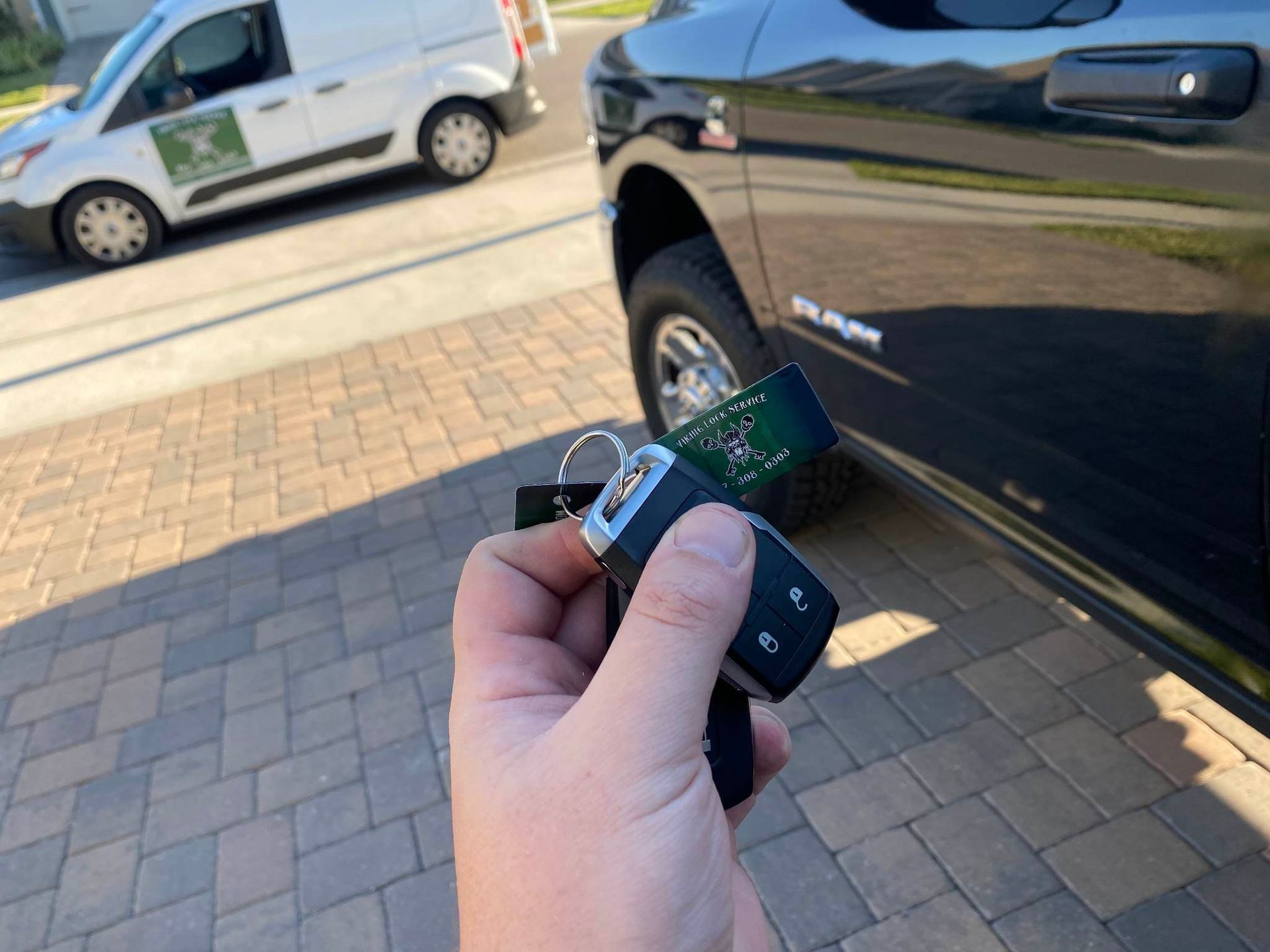 A person is holding a remote control in front of a car.