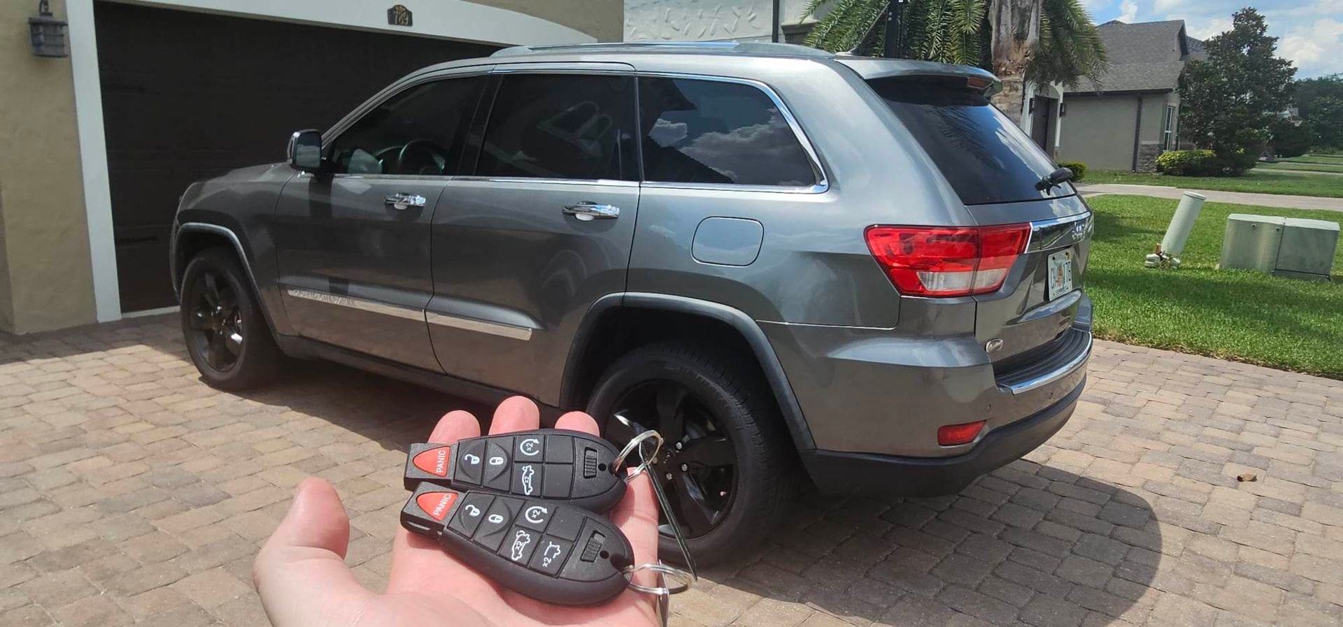 A person is holding a remote control in front of a jeep.