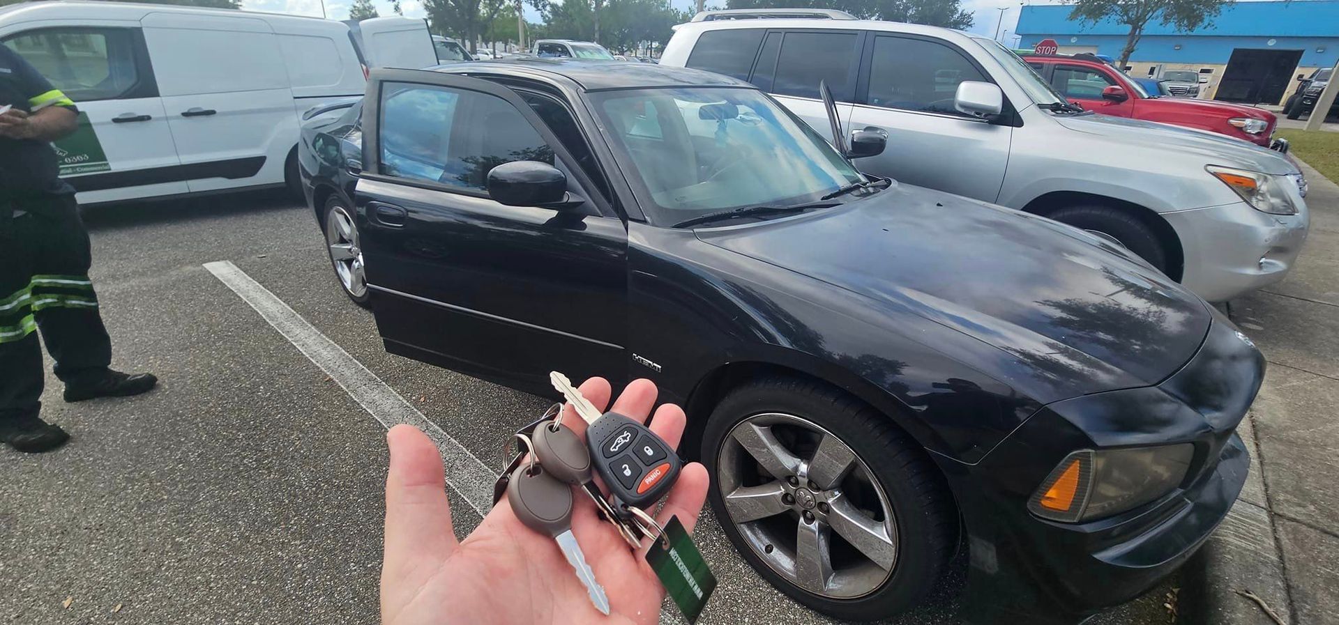 A person is holding a car key in front of a black car.