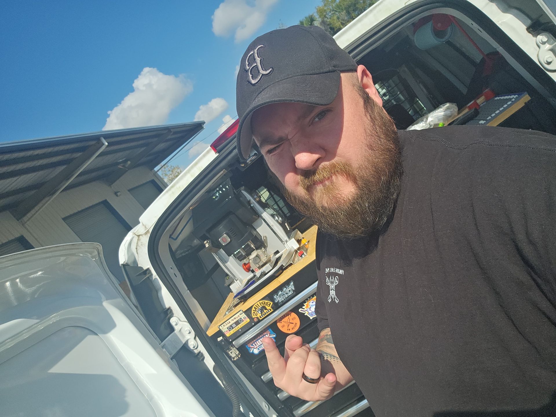 A man with a beard and a hat is standing in the back of a truck.