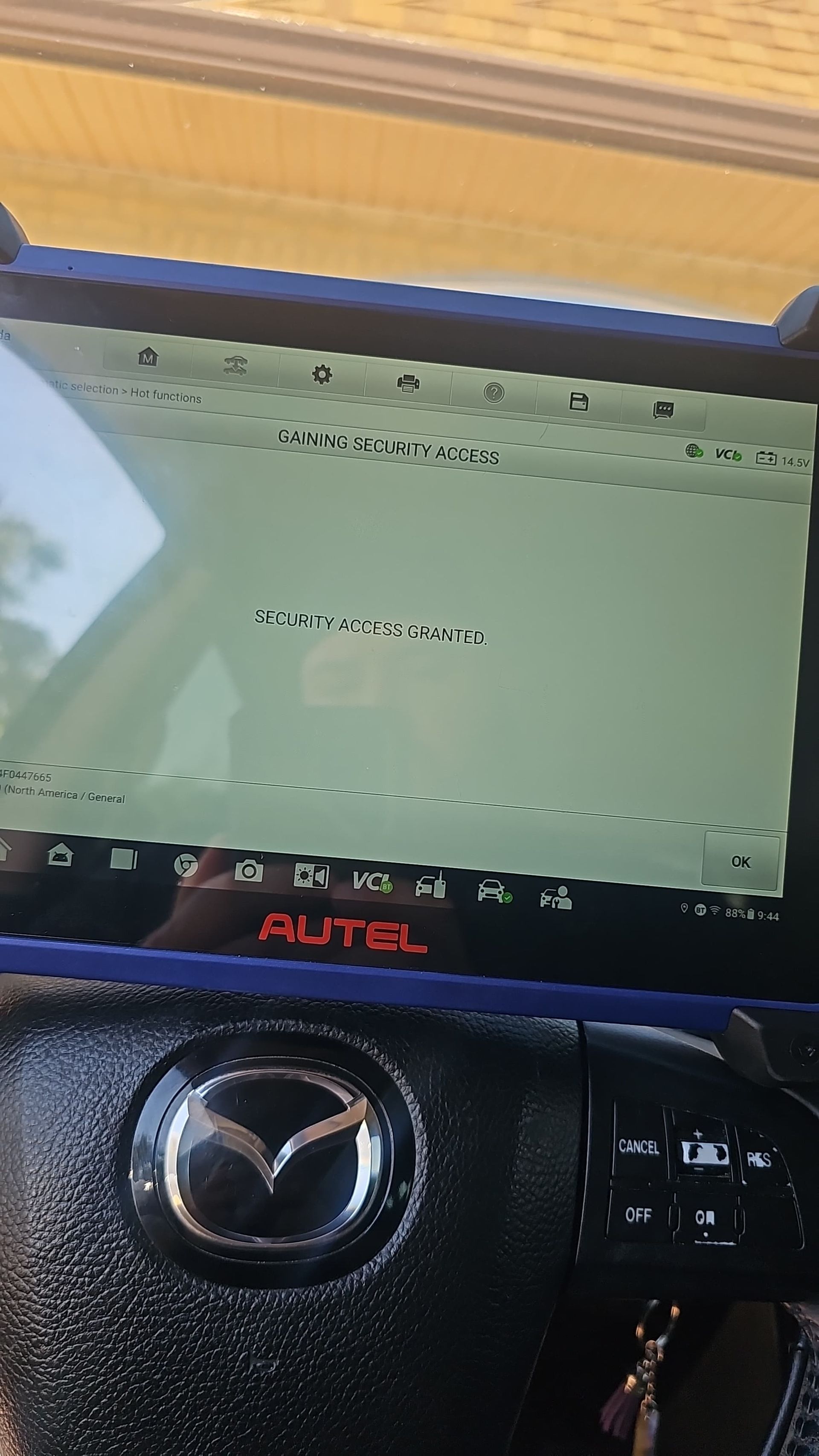 A tablet is sitting on the steering wheel of a car.