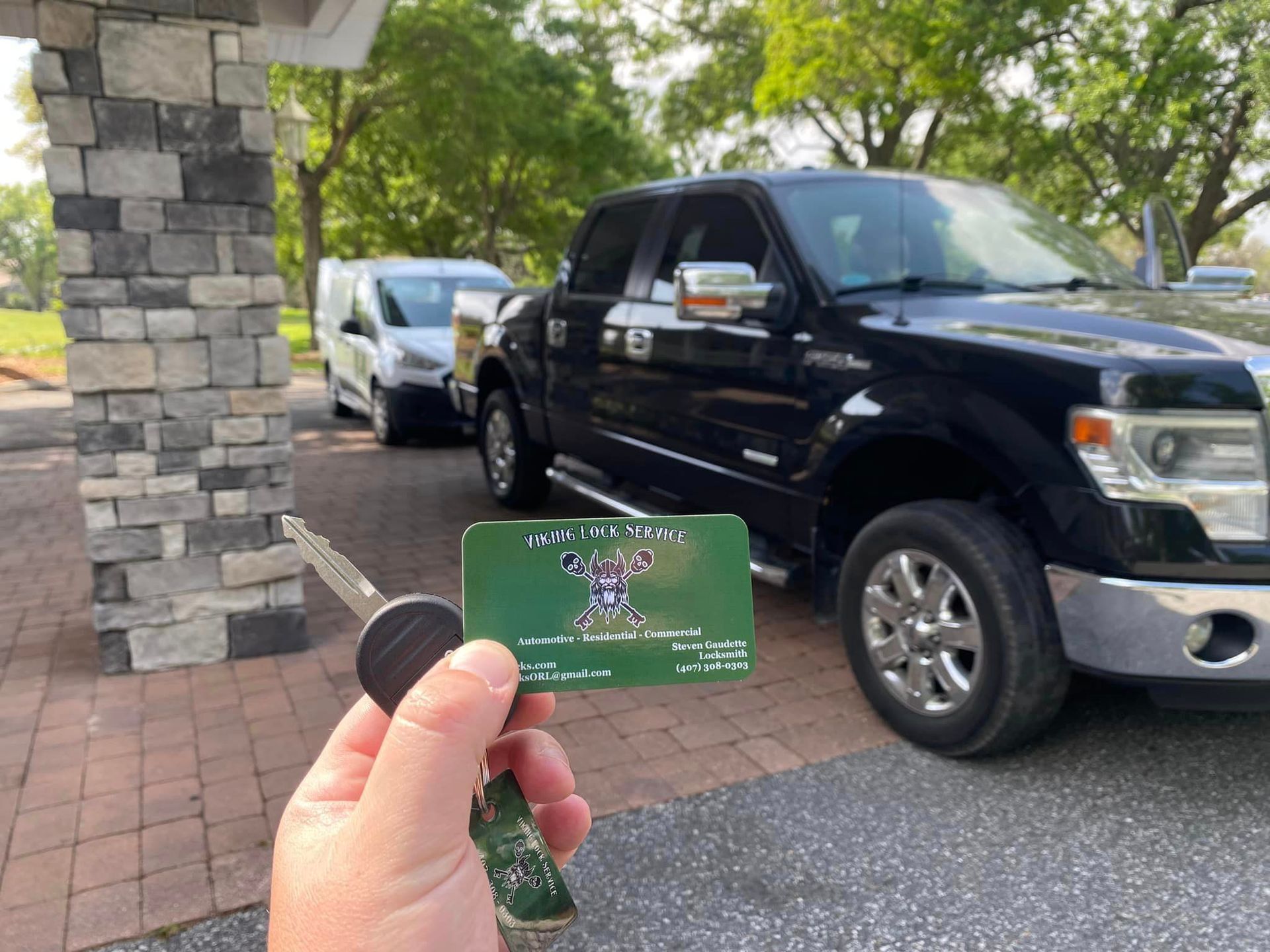 A person is holding a key in front of a black truck.