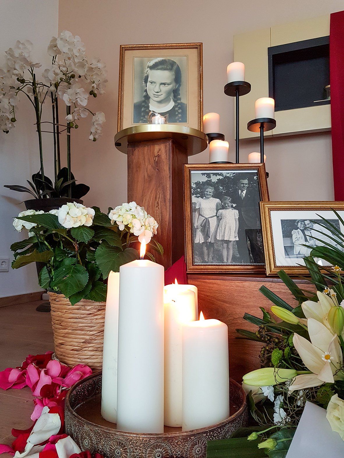 Eine Ausstellung von Kerzen Blumen und ein Bild einer Frau