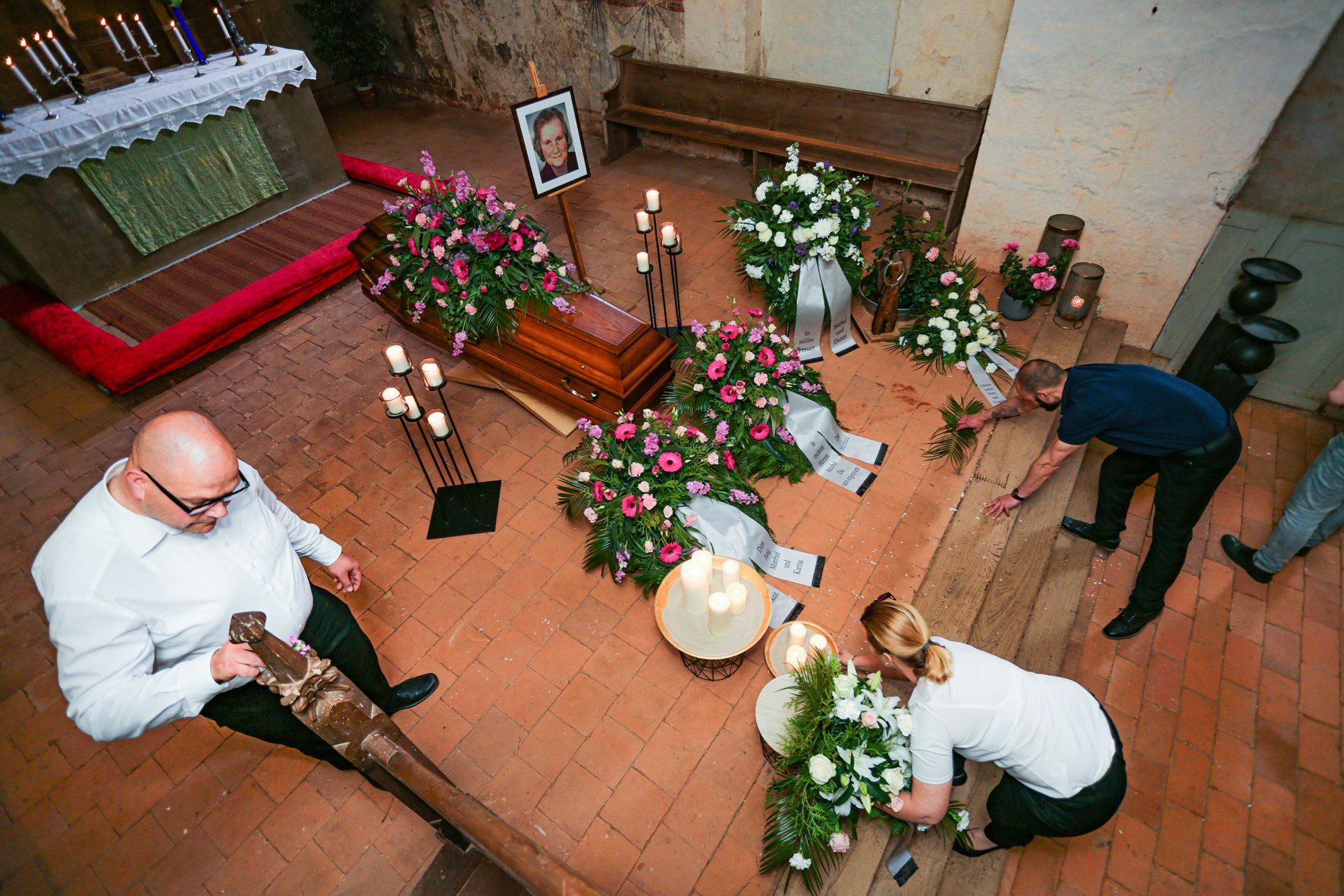 Ein Sarg ist in einer Kirche von Blumen und Kerzen umgeben