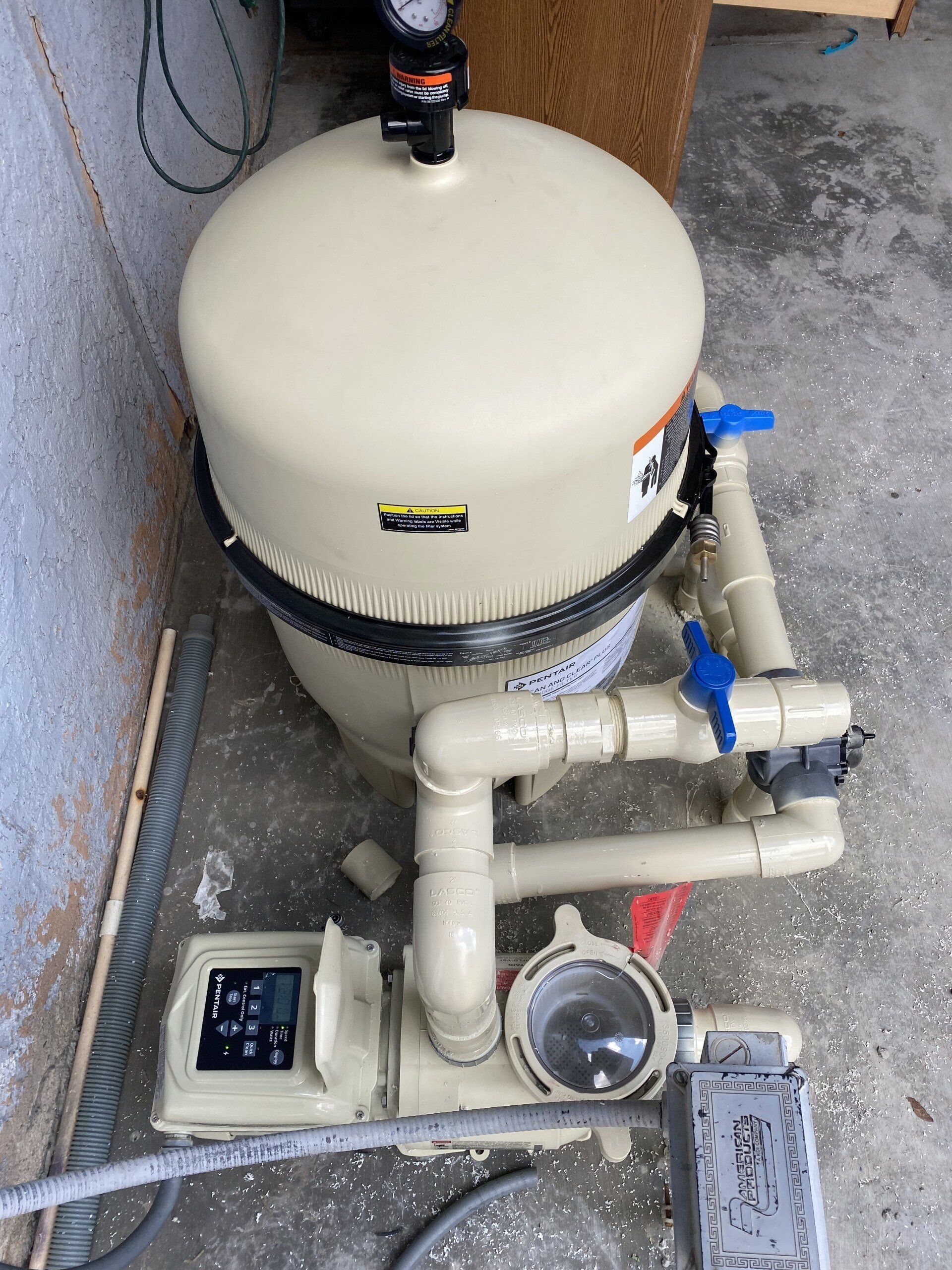 A swimming pool filter is sitting on the ground next to a wall.