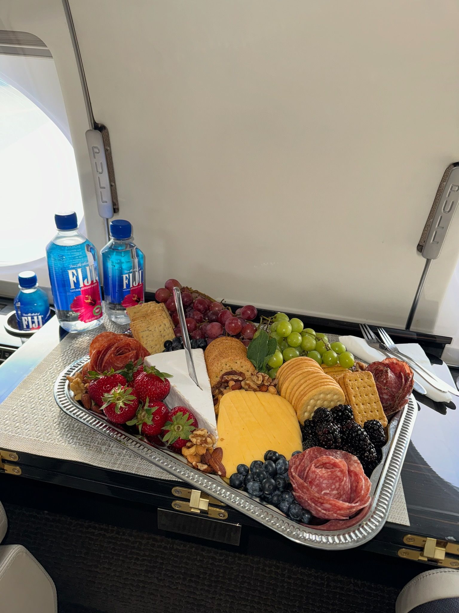 A tray of food is sitting on a table on an airplane.
